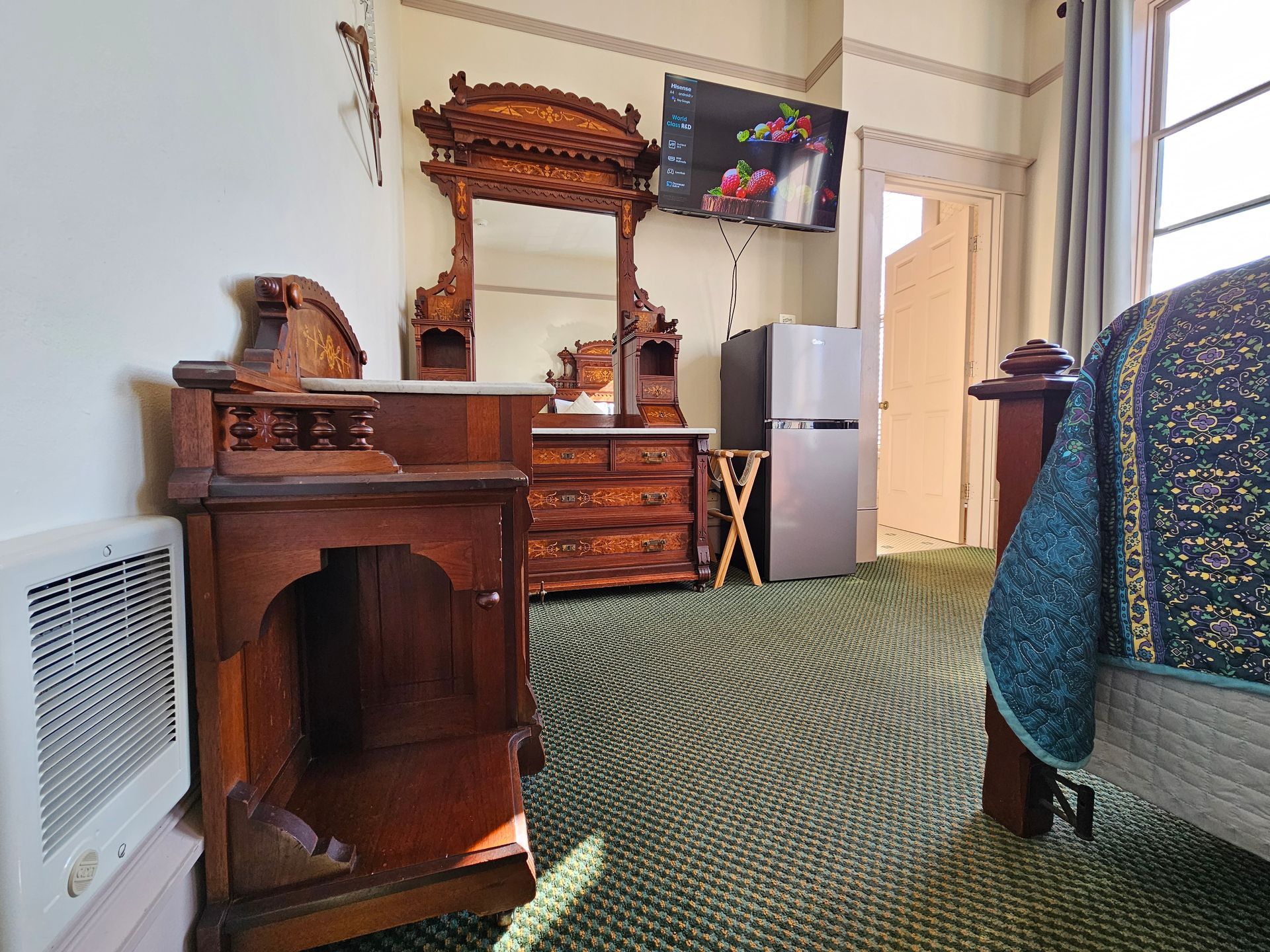 Bedroom with matching dresser to bed, fridge, and TV. 