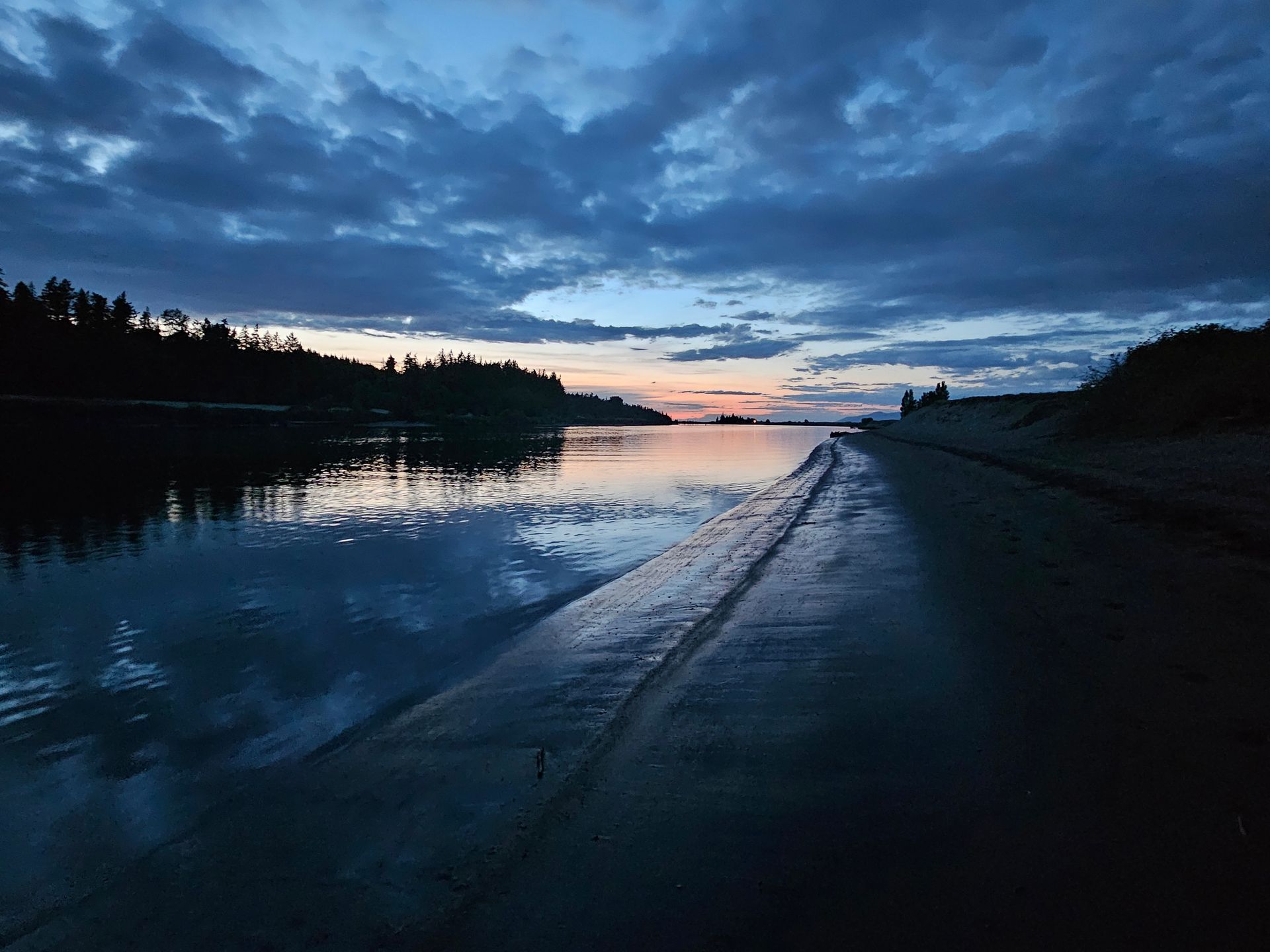 A road leading to a body of water with a sunset in the background.