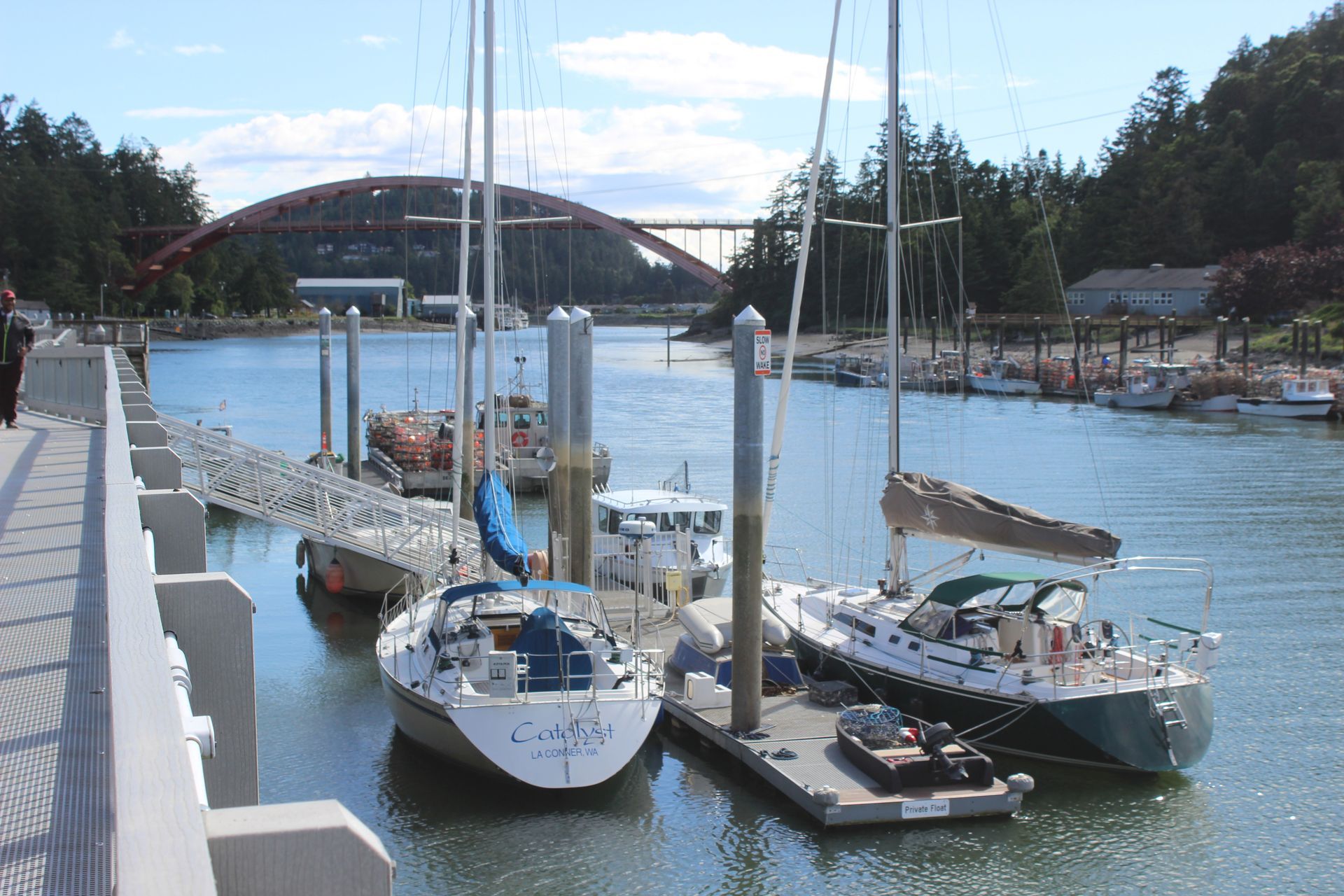 Boats are docked in a harbor with a bridge in the background