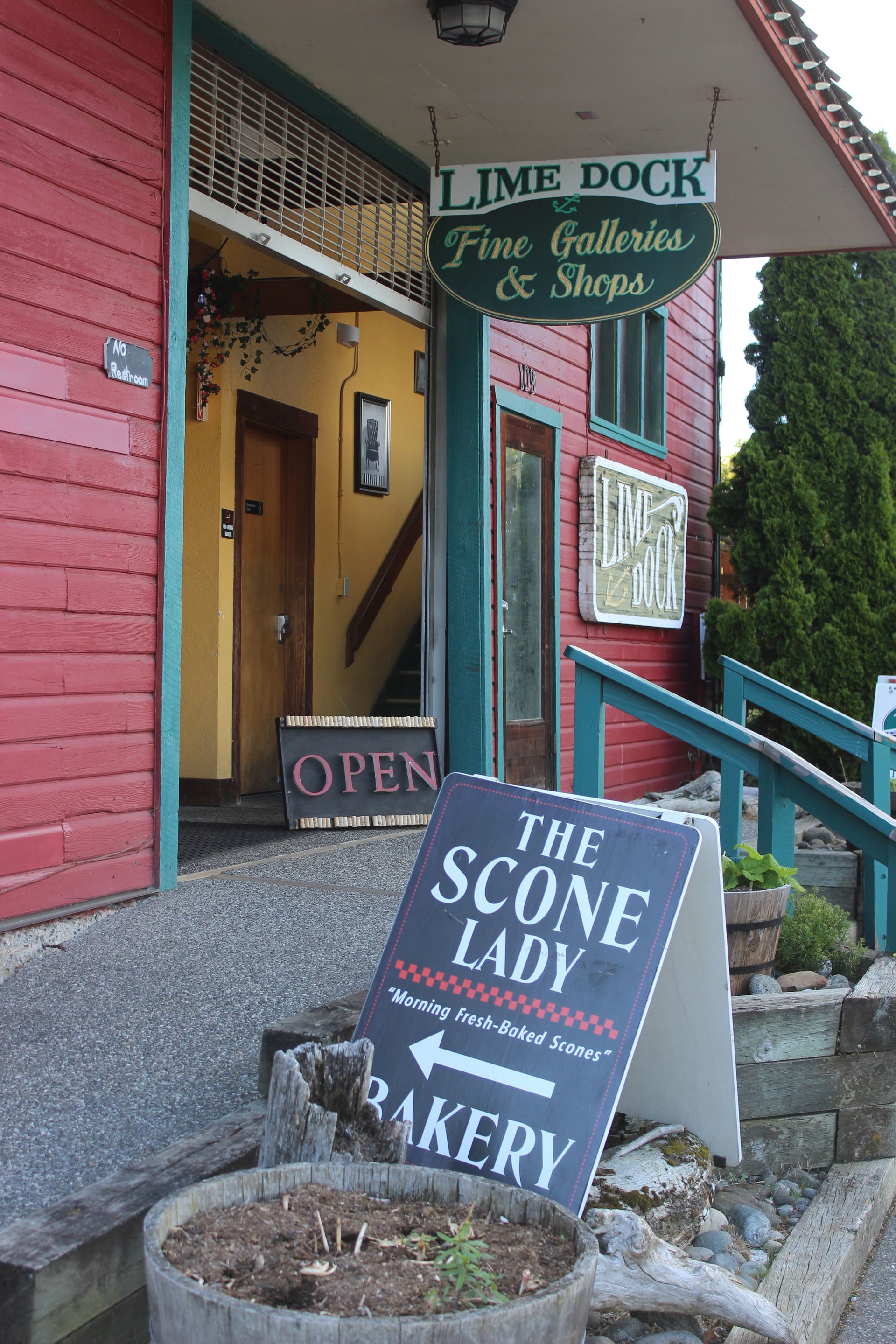 A sign for the scone lady bakery is in front of a red building