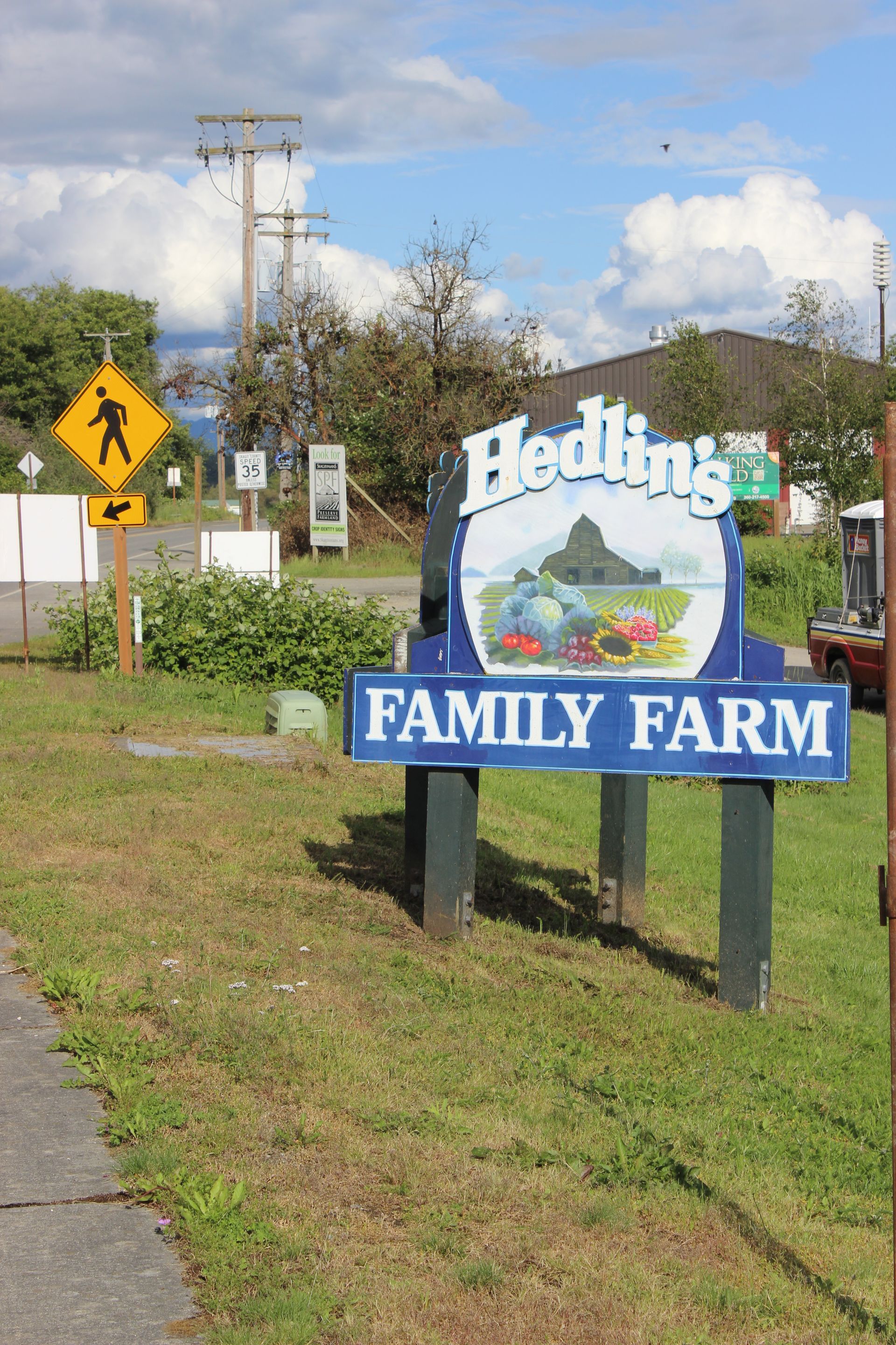 A sign for the hedlins family farm is in the grass