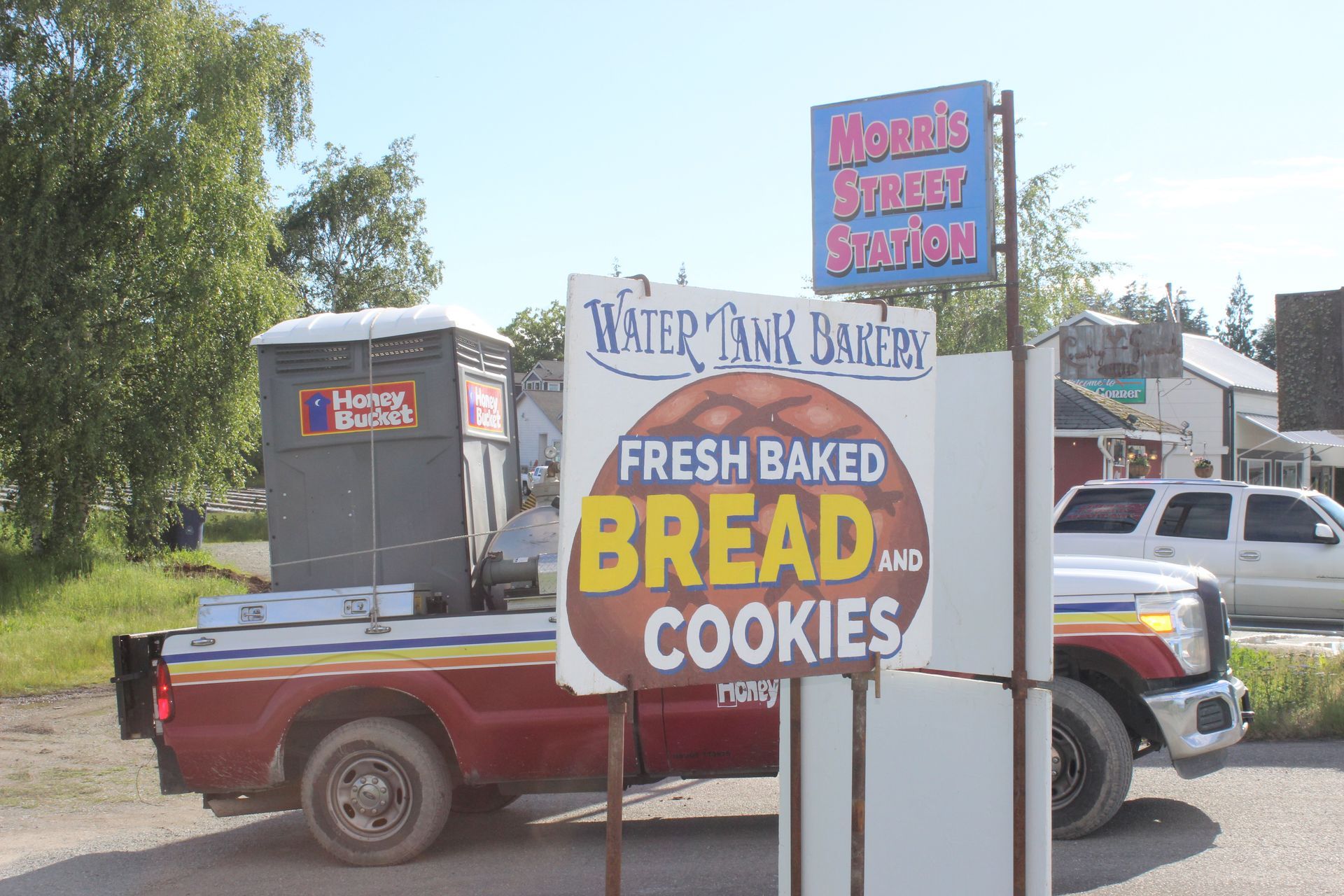 A truck is parked in front of a sign that says fresh baked bread and cookies