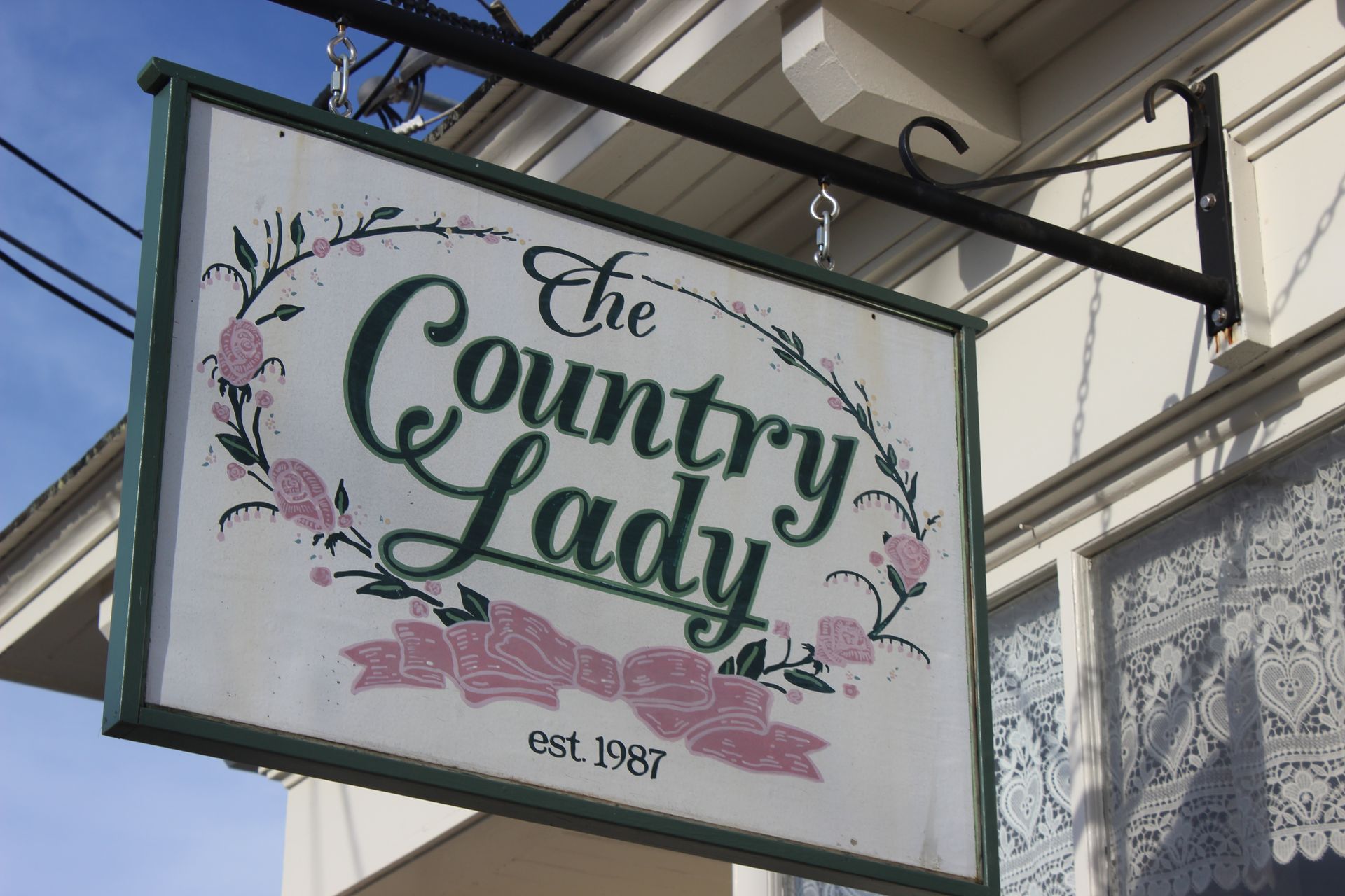 A sign for the country lady hangs from the side of a building