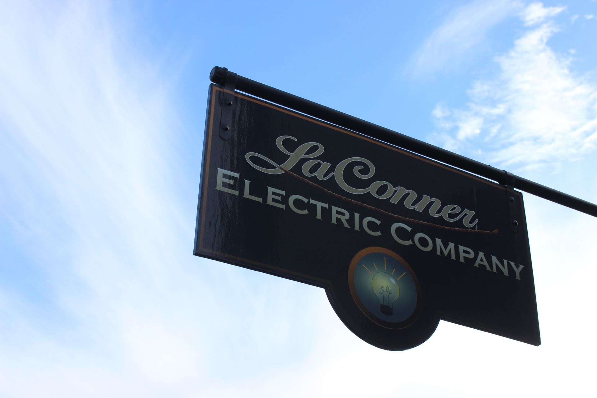 A sign for la conner electric company hangs from a pole