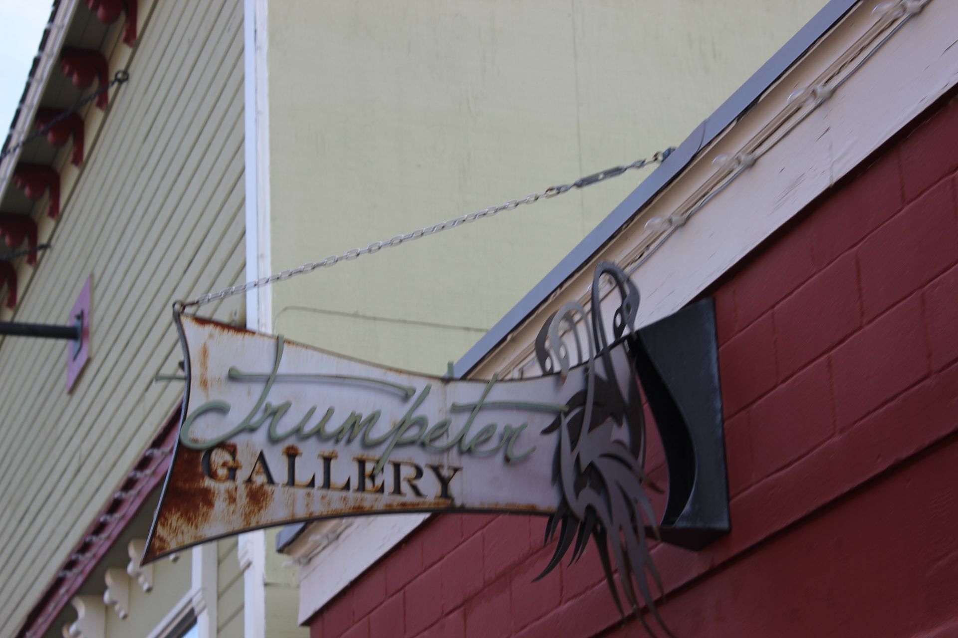 A sign for the trumpeter gallery hangs from the side of a building