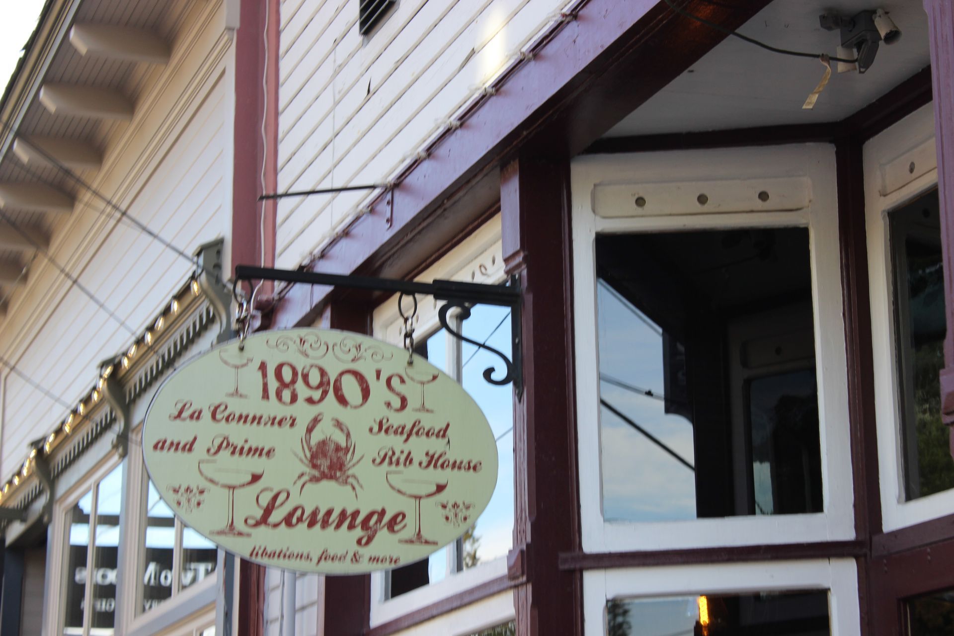 A sign for 1890 's lounge hangs outside of a building