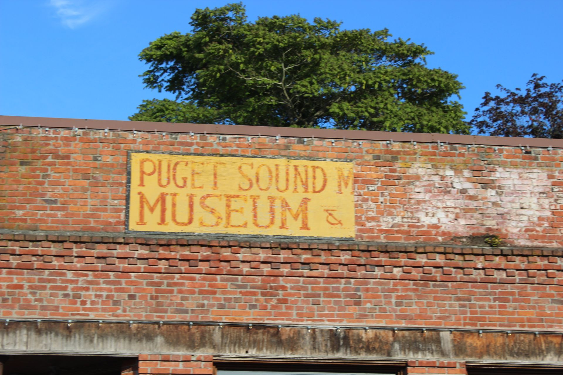 A yellow sign on a brick building says puget sound museum