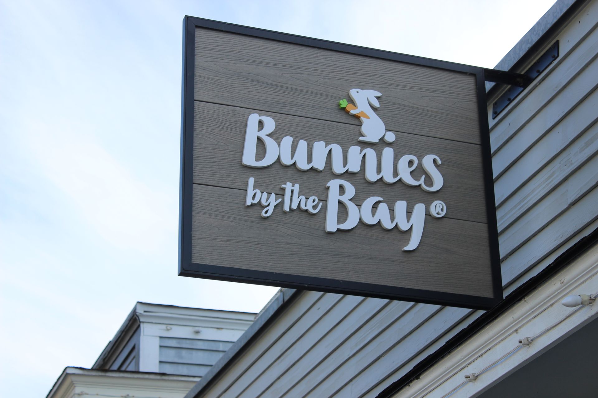 A sign for bunnies by the bay hangs from the side of a building