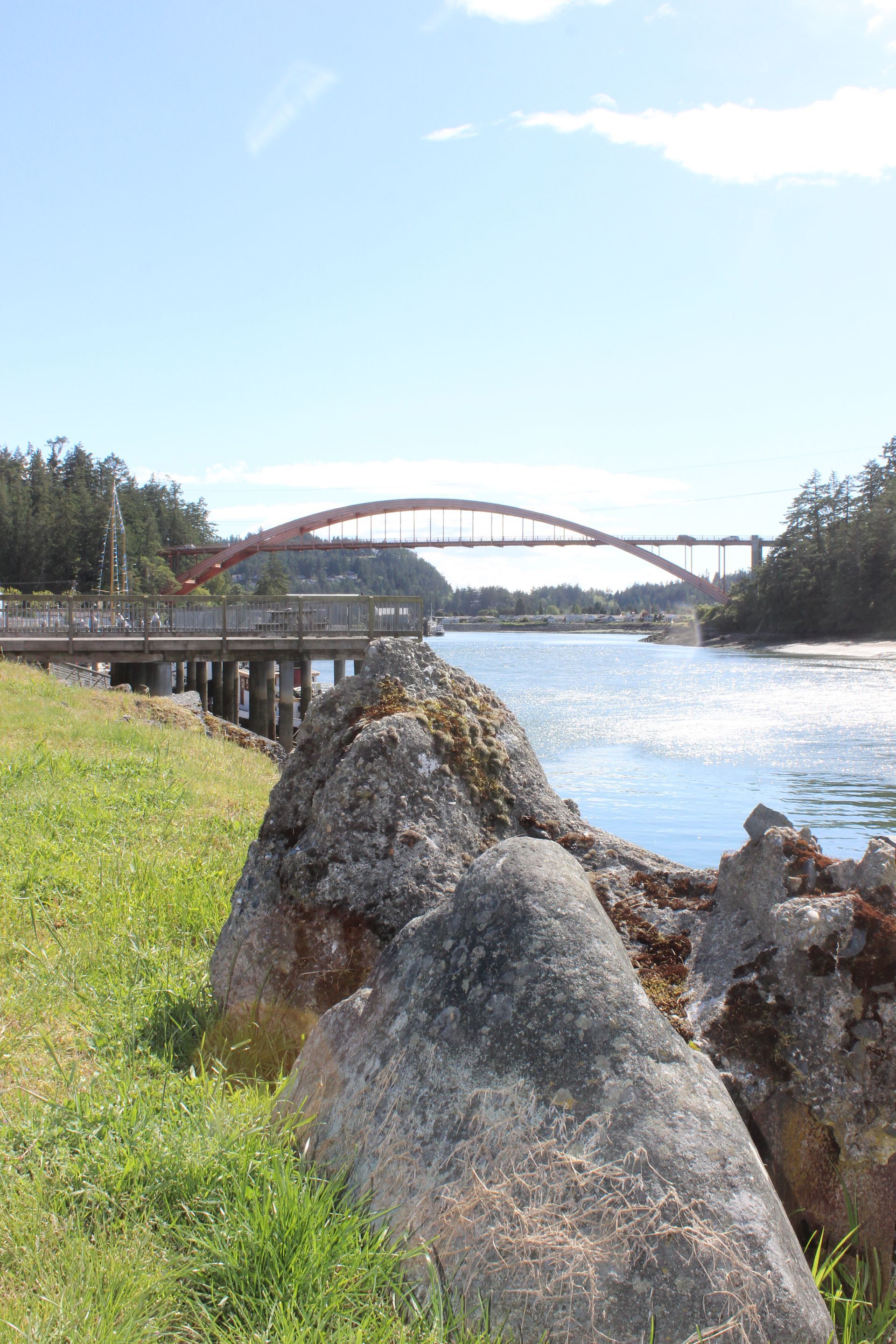 A bridge over a body of water with a large rock in the foreground.