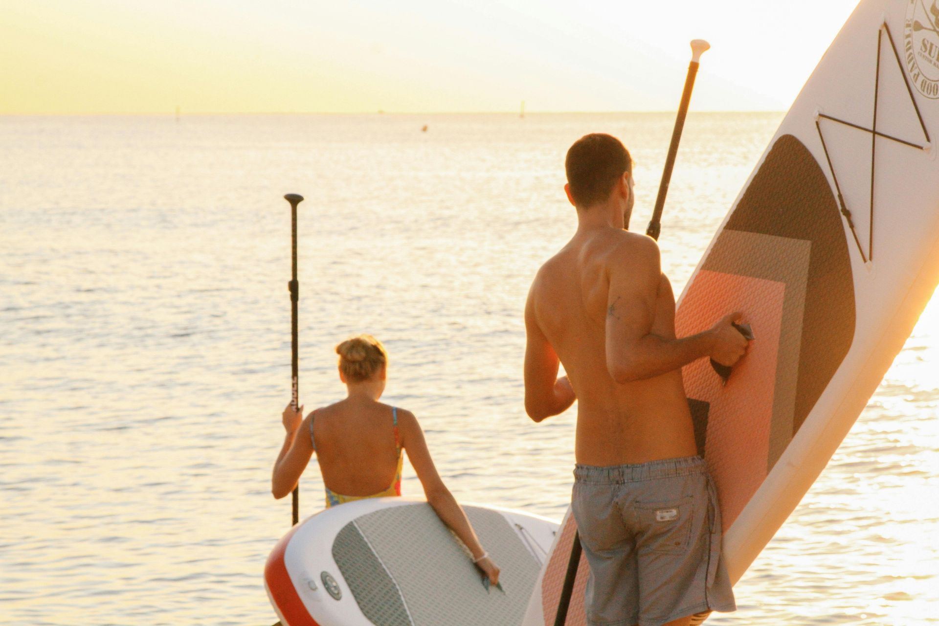 A man and a woman are paddle boarding in the ocean.