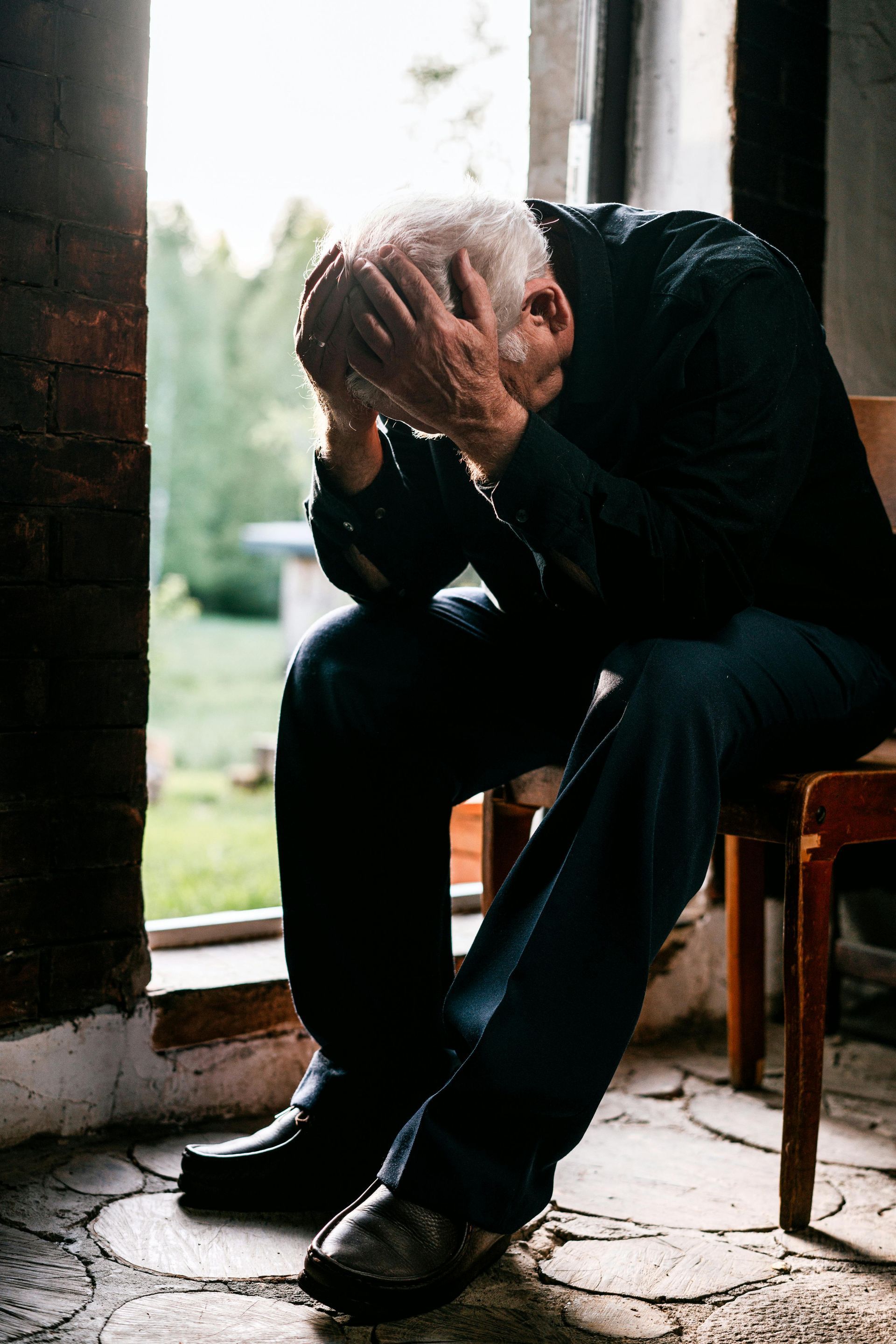 A young man is sitting at a table with his head down.