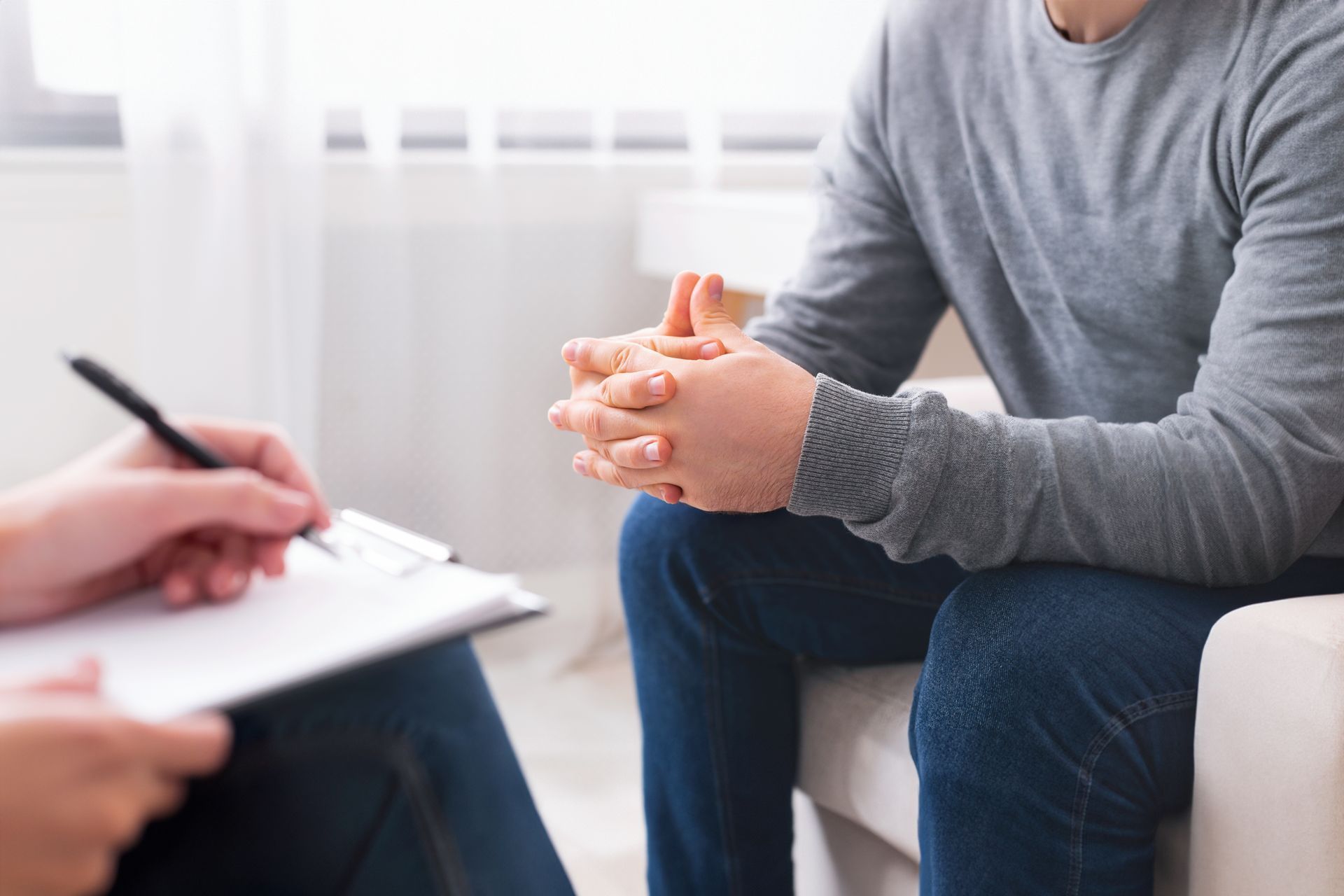 A man is sitting on a couch talking to another man.