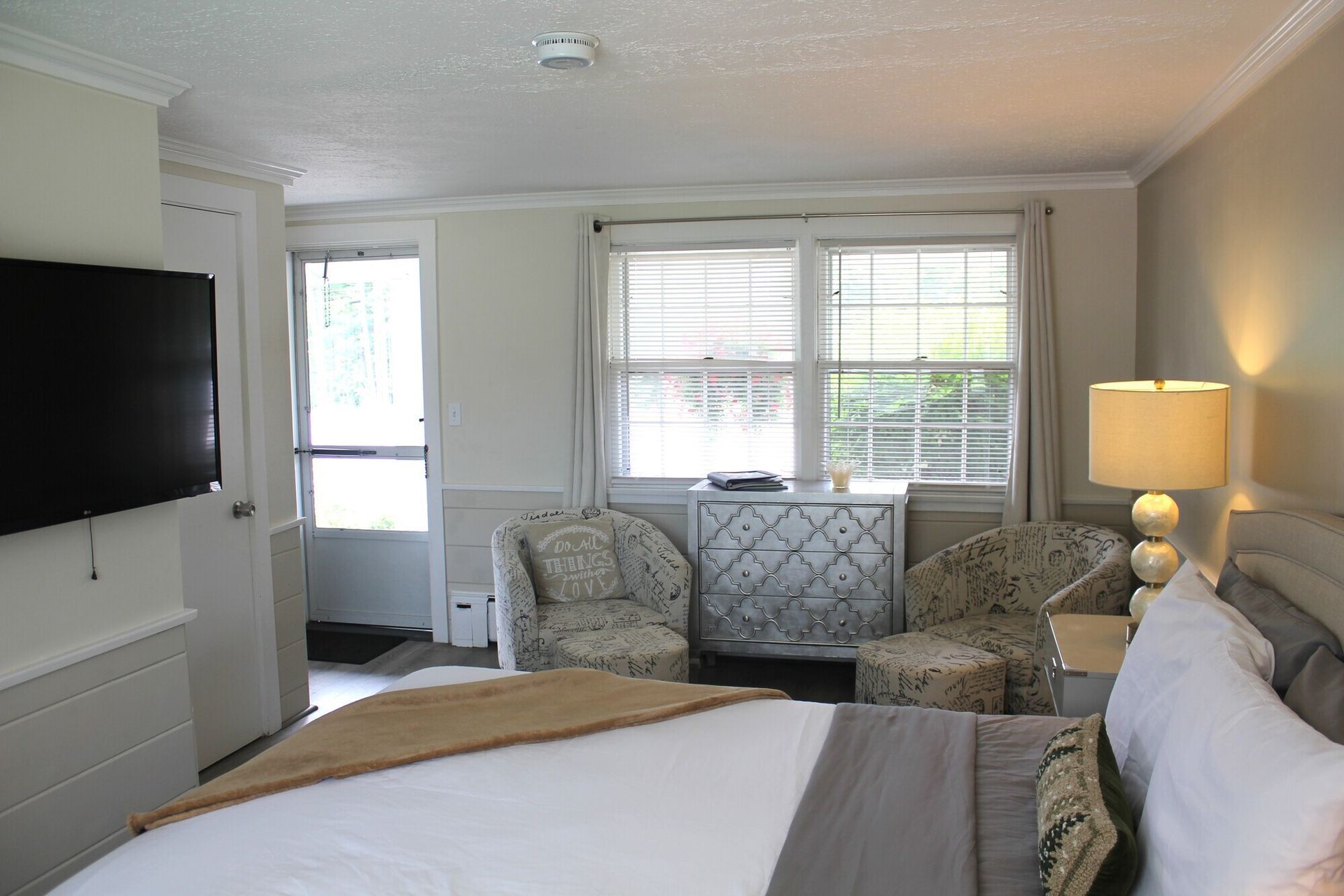 Bedroom with bed, seating area, TV, and door to outside.