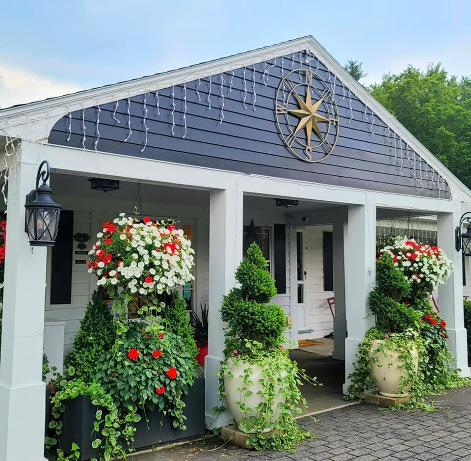 Entrance to a building with nautical decor; hanging baskets and topiary flank the doorway.