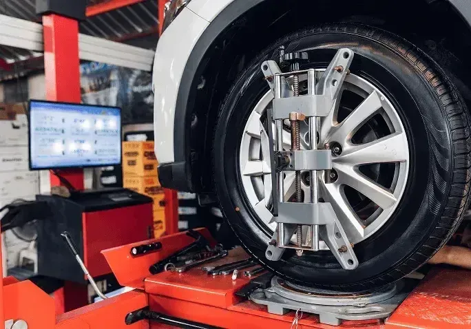 White Vehicle on Lift for Wheel Alignment | Rux Auto Garage Inc