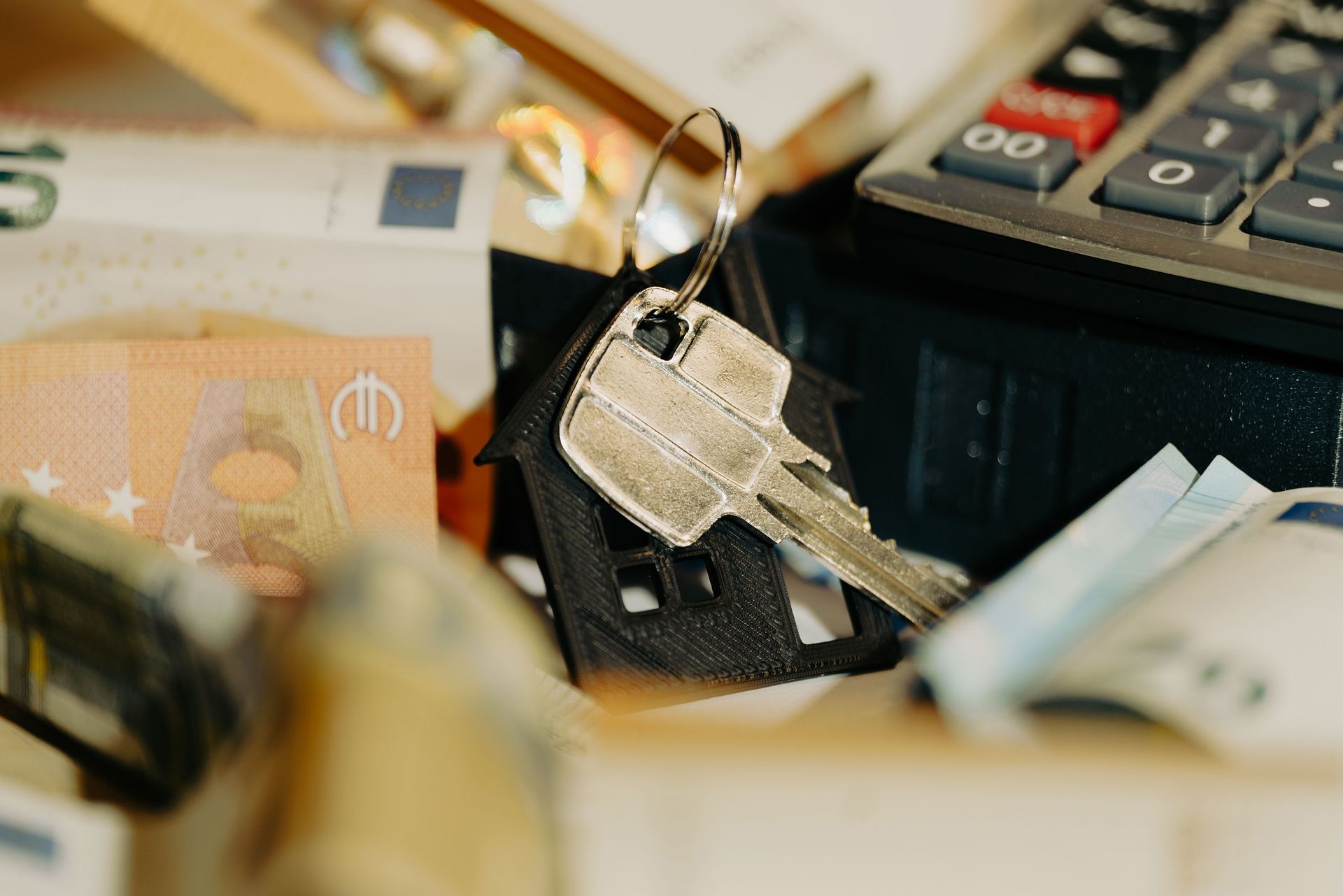 Close-up of a keyring with silver keys on a cluttered desk beside papers and office items