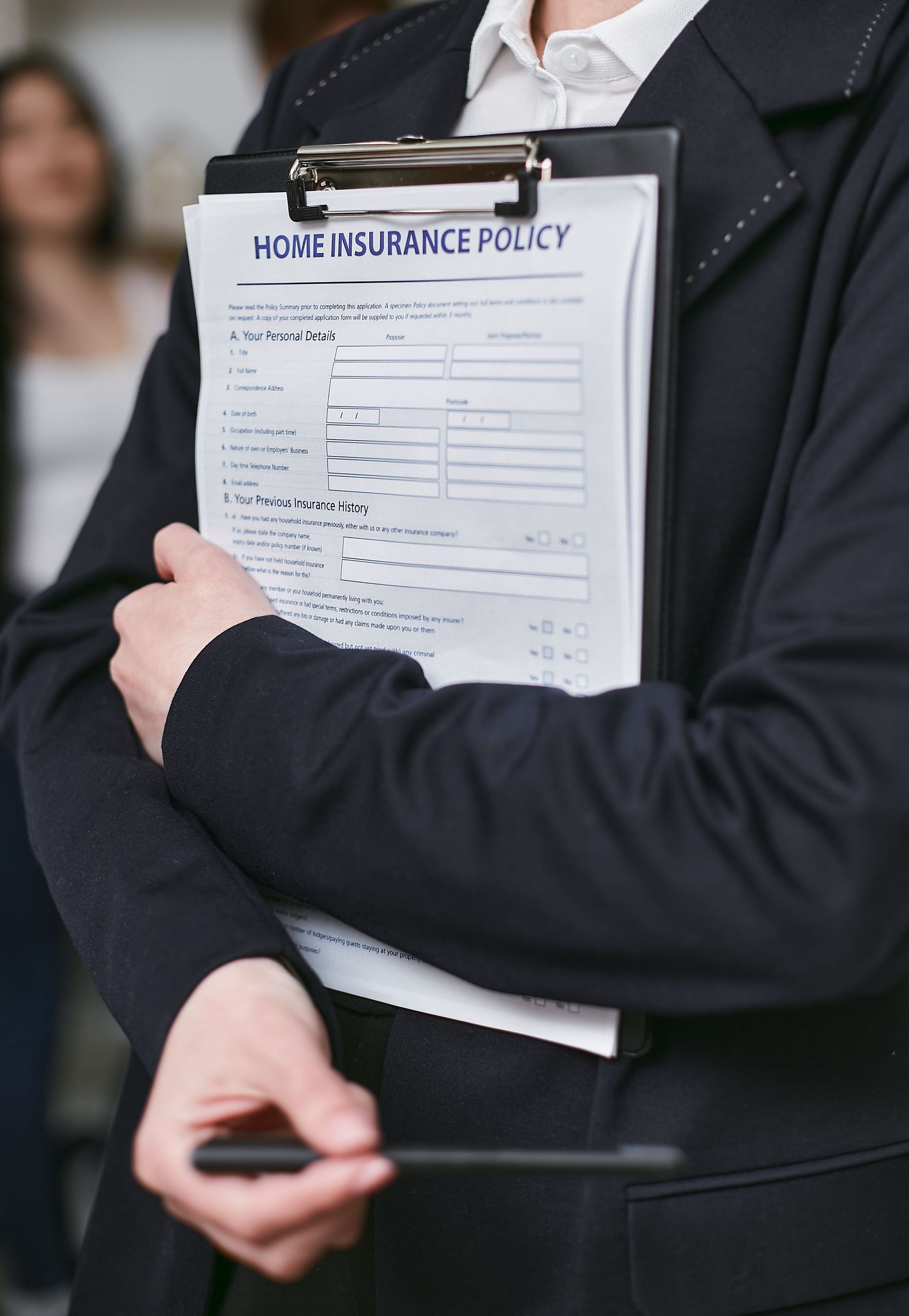 Person holding a clipboard labeled “Home Insurance Policy” in a black suit.