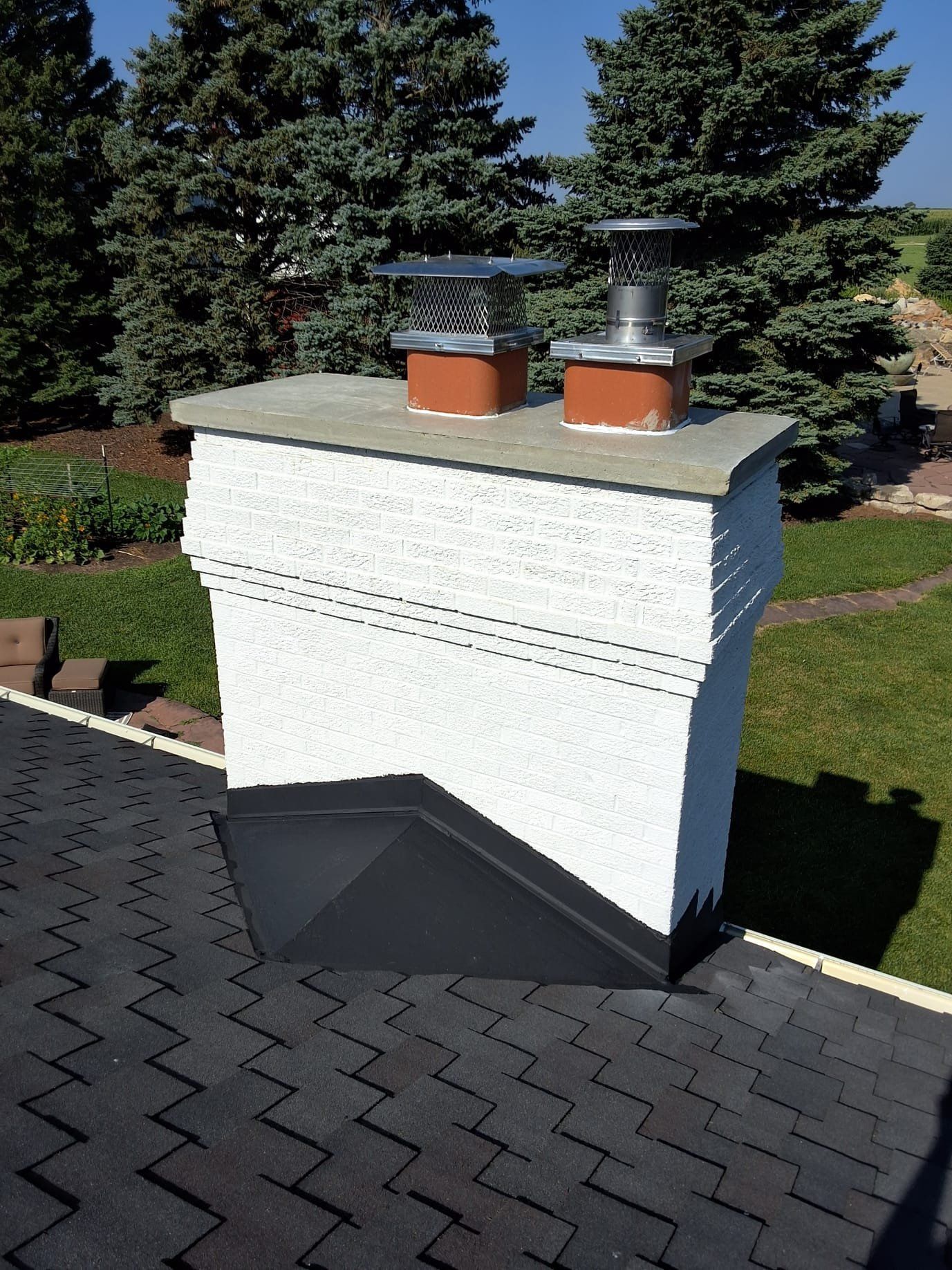 A chimney on top of a roof with trees in the background