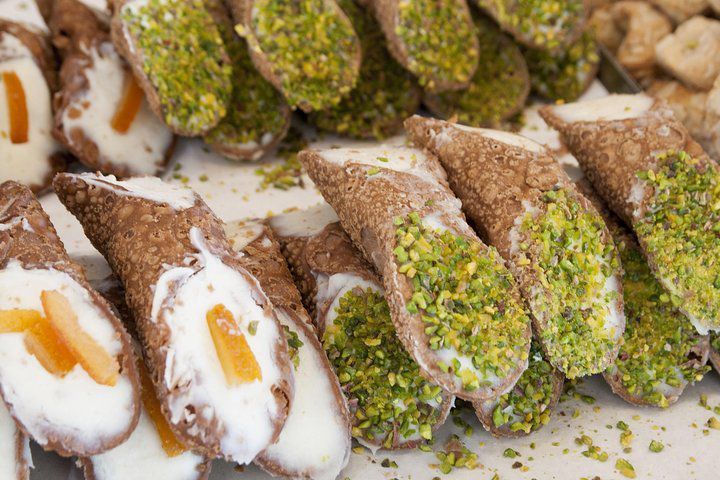 Cannoli assortiti con ripieno di crema bianca e al pistacchio, serviti su un vassoio.