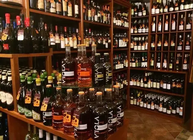 Scaffali di un negozio di liquori pieni di bottiglie di vino e whisky di vario tipo.