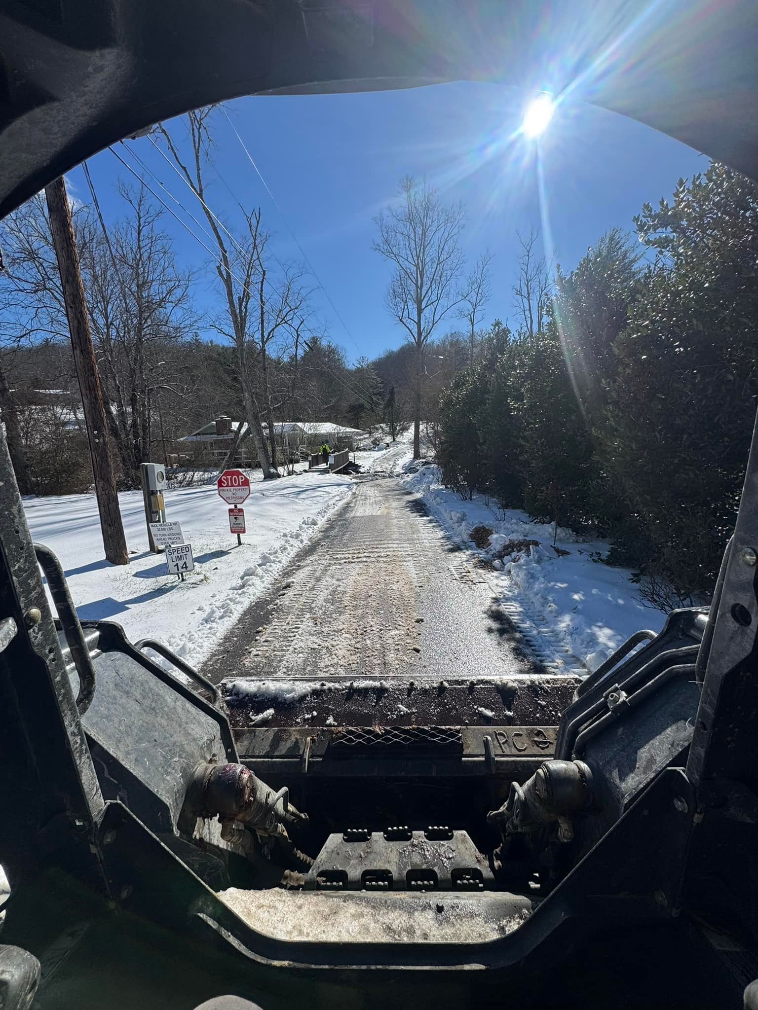 A yellow snow plow is parked in the snow on the side of the road.