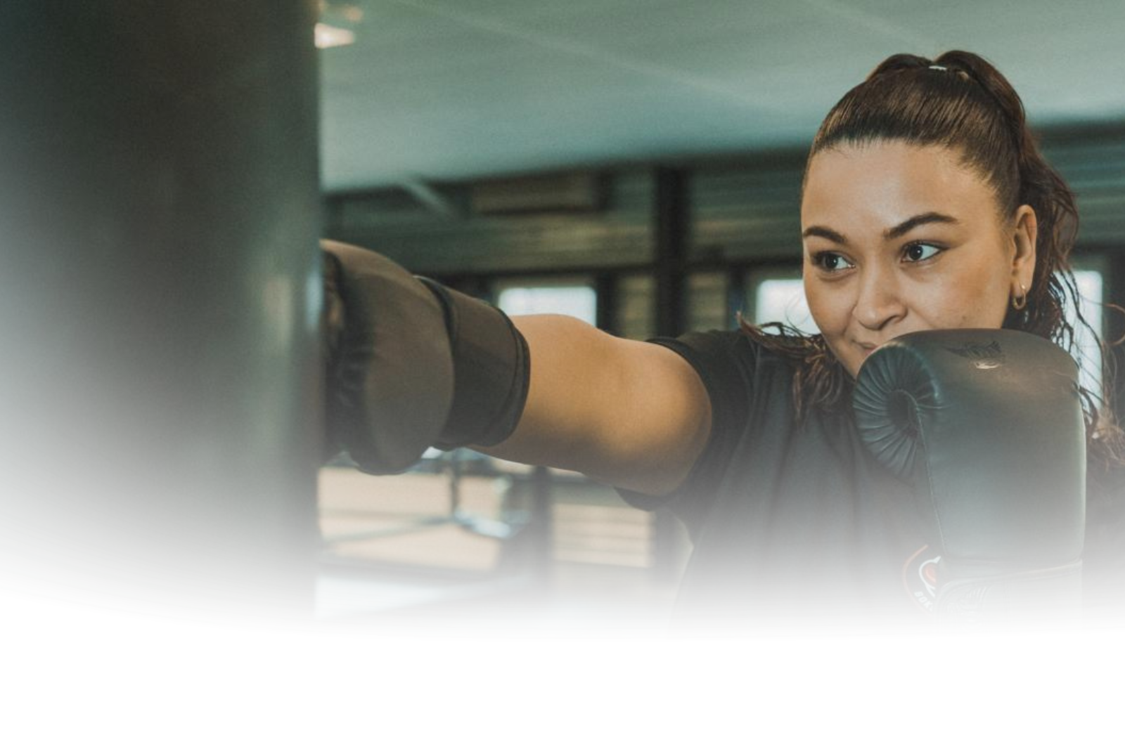 Iemand met bokshandschoenen slaat op een boksbal in een sportschool.