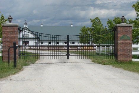 A metal gate leading to a farm with a white building in the background