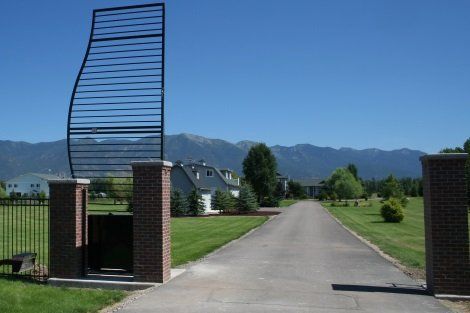 A driveway leading to a house with mountains in the background
