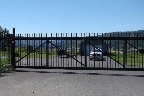 A car is parked in a driveway behind a fence