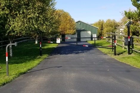 A road with a fence and a green building in the background