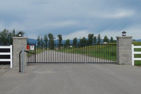 A black gate with a white fence in the background