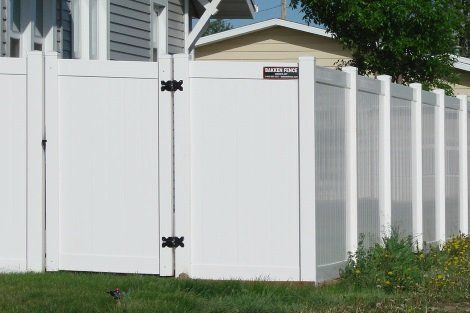 A white fence with a gate in front of a house.