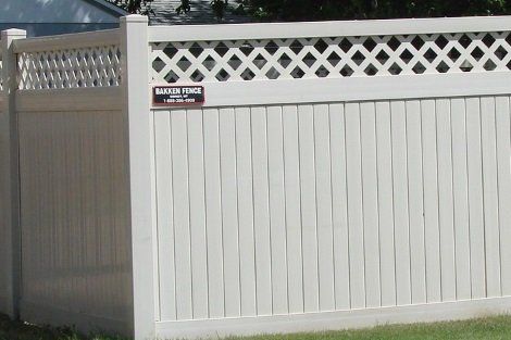 A white lattice fence with a sign that says master fence