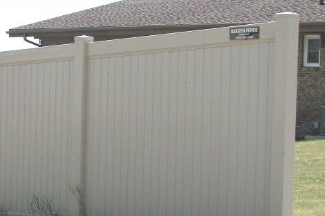 A white vinyl fence is in front of a house.