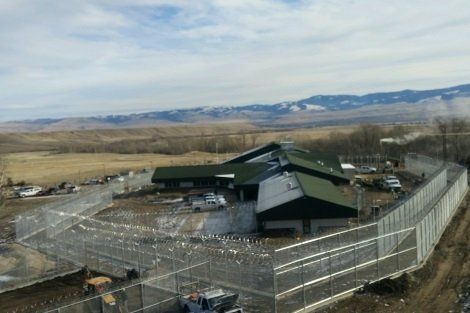An aerial view of a building behind a fence with mountains in the background.