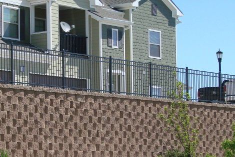 A house with a fence around it and a satellite dish on the balcony.