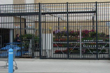 A shopping cart is parked in front of a walmart fence