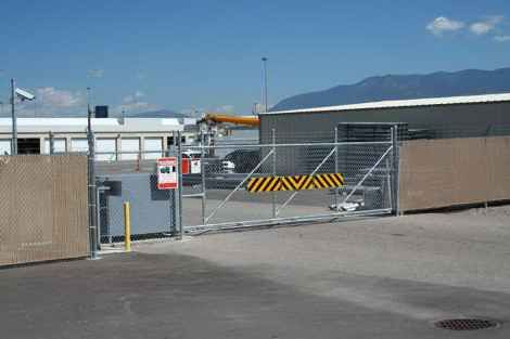 A fence with a warning sign on it is surrounding a parking lot.
