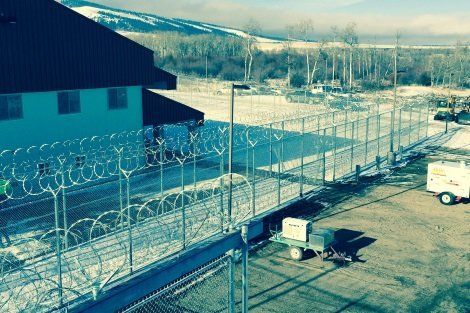 A barbed wire fence surrounds a building in the snow
