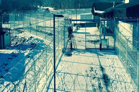 A barbed wire fence surrounds a building in the snow