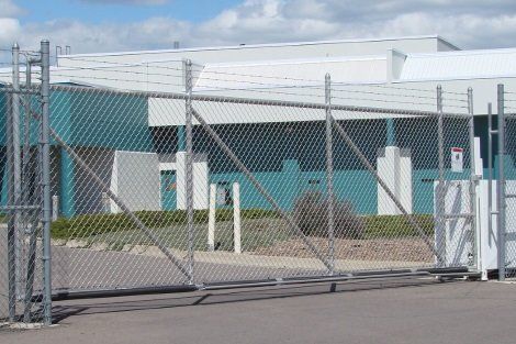 A chain link fence with a sliding gate in front of a building