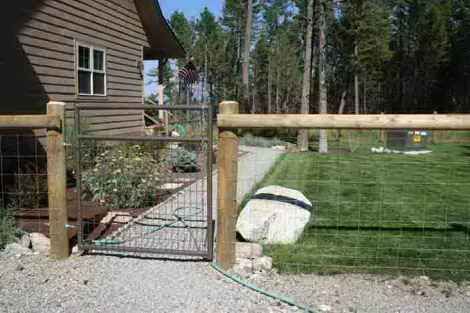A wooden fence with a gate in front of a house.