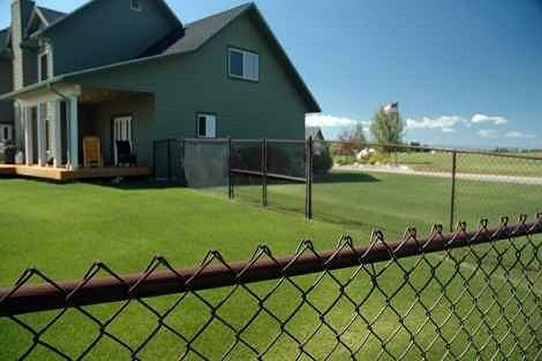 A chain link fence is in front of a house.