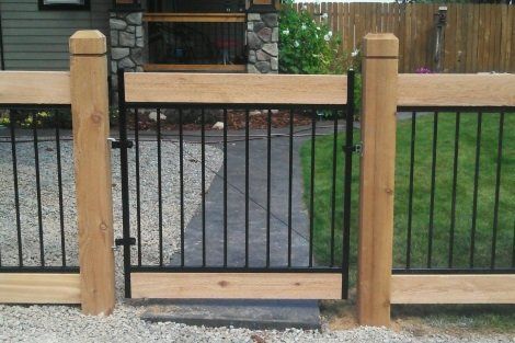 A wooden fence with a metal gate in front of a house