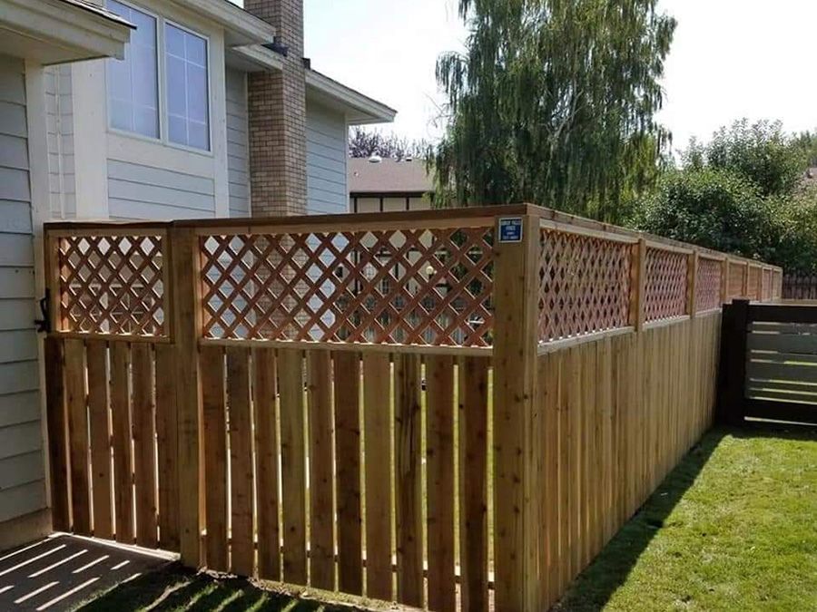 A wooden fence with a lattice surrounding it is in front of a house.