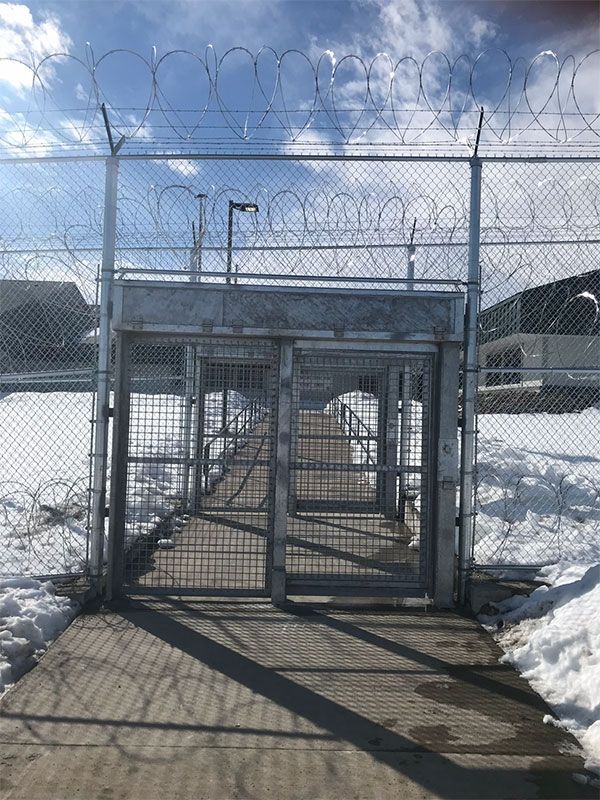 A barbed wire fence surrounds a bridge in the snow.
