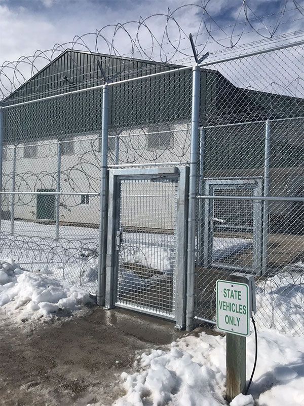 A barbed wire fence surrounds a building with a sign that says state vehicles only.