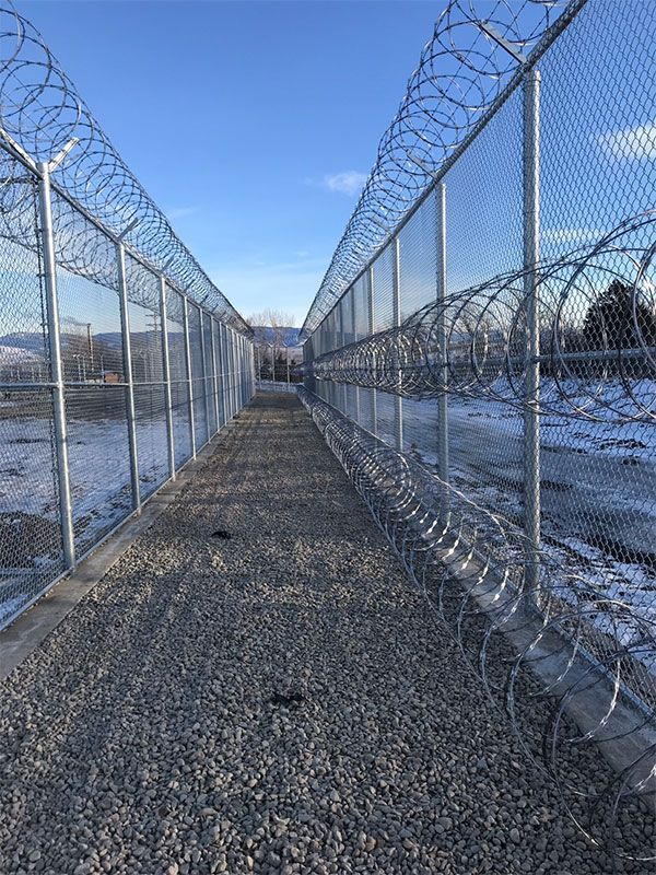 A chain link fence with barbed wire along the side of it.
