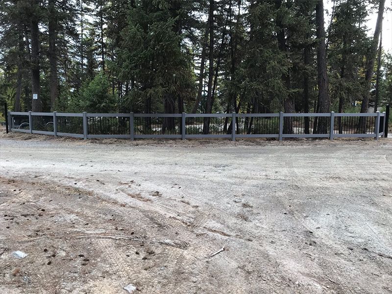 A fence surrounds a dirt road in the middle of a forest.