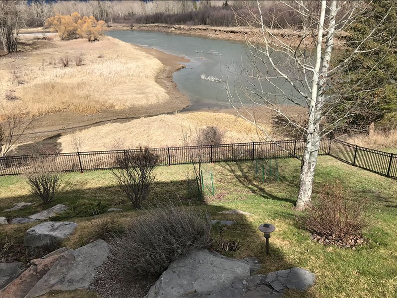 A view of a lake from a fenced in yard.